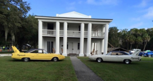 Two classic cars in front of a mansion